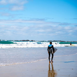 Rear view of surfer walking on beach