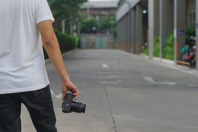 Midsection of man photographing on street