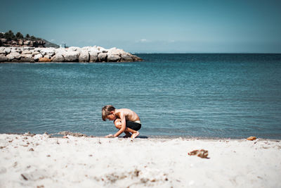 Full length of shirtless man on beach