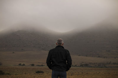 Rear view of adult man on field in mist. cabo de gata nature park, almeria, spain