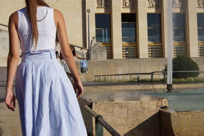 Rear view of woman standing by building in city