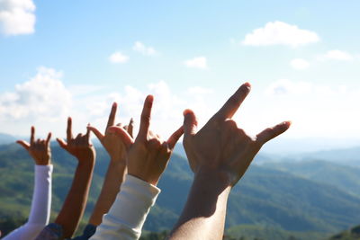 Cropped image of hands gesturing against sky