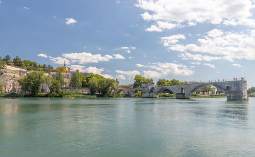 Bridge over river by buildings against sky