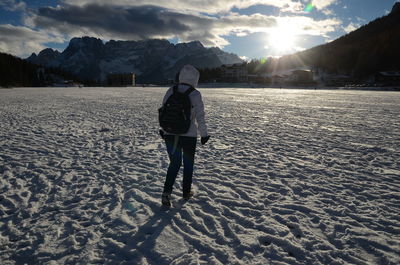 Rear view of woman standing on snow covered landscape