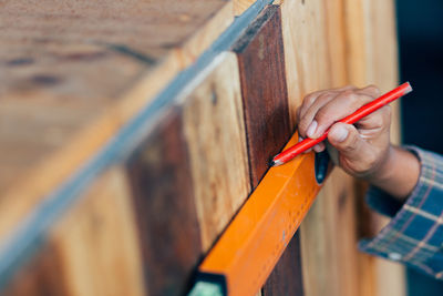 Close-up of man hand working on wood with pencil and spirit