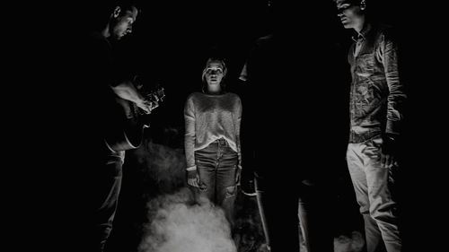 Digital composite image of people standing in illuminated dark