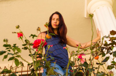 Beautiful young woman standing by flowering plants