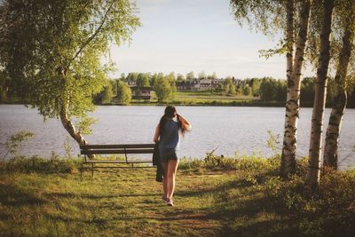 Rear view of woman standing at lakeshore