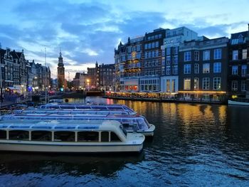 Boat moored on river by buildings in city against sky