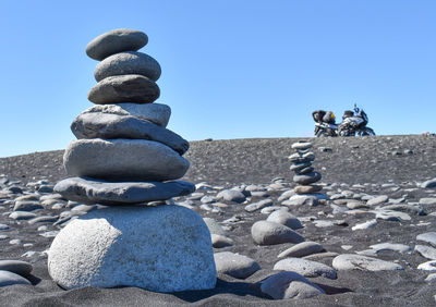 Stack of stones on beach against clear blue sky
