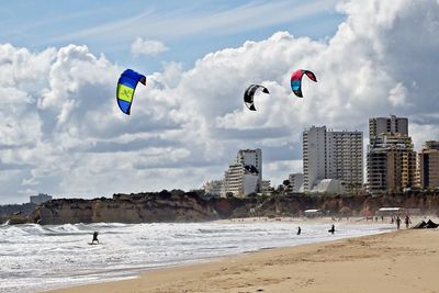 People paragliding at beach against sky