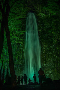 People standing by waterfall in forest