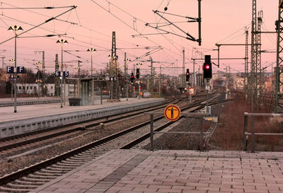 Railroad station platform against sky at sunset