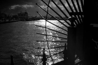 Silhouette of bridge over sea against buildings