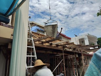 Low angle view of men working at construction site against sky