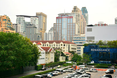 Cars on road by buildings in city against sky