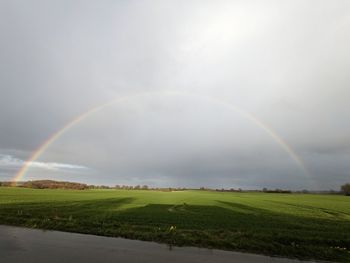 Scenic view of rainbow over field against sky