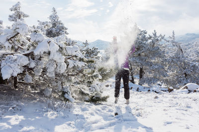 Young woman snow forest. a beautiful brunette enjoys the first fluffy clean snow near a snow-covered 