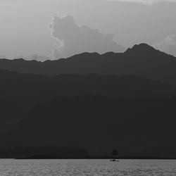 Scenic view of sea and silhouette mountains against sky