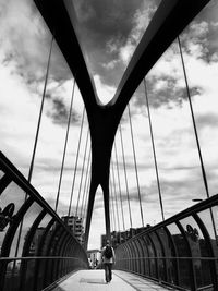 Low angle view of suspension bridge against cloudy sky