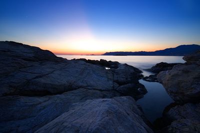 Rock formations in sea against sky during sunset