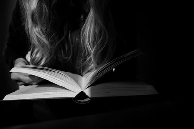 Close-up of open book on table against black background