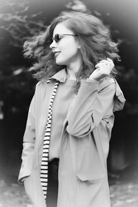 Young woman looking away while standing outdoors