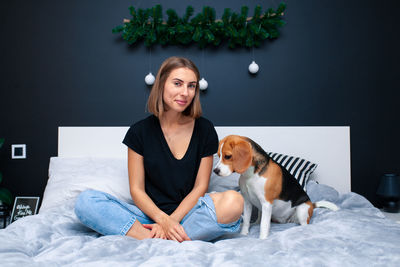 Young woman with dog sitting on bed