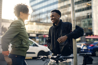 Smiling friends standing against cars on street in city