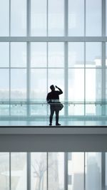 Rear view of silhouette man standing against window