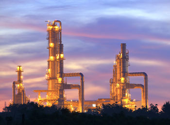 Illuminated factory against sky at sunset