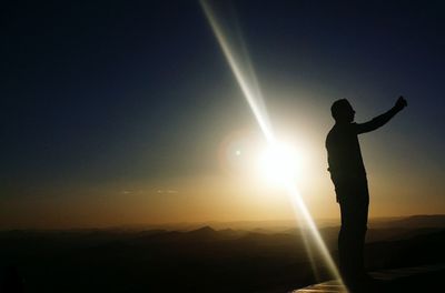 Silhouette man standing against sky during sunset