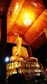 Low angle view of statue against illuminated temple