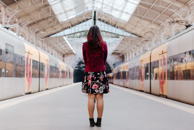 Rear view of woman standing on train at railroad station