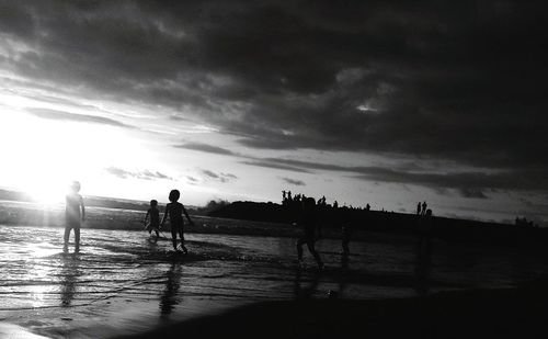 Silhouette people on beach against sky