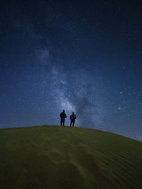 People standing on field against sky at night