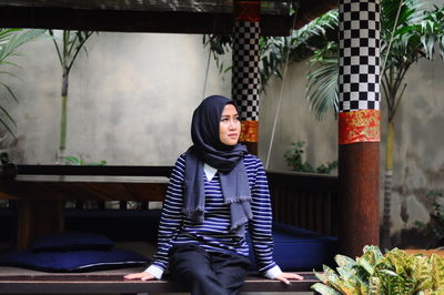 Woman in headscarf sitting indoors