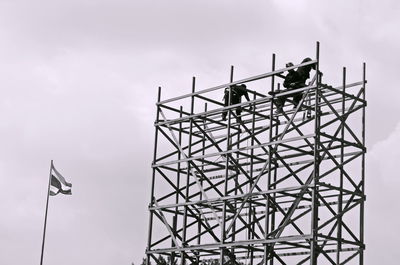 Low angle view of silhouette crane against sky