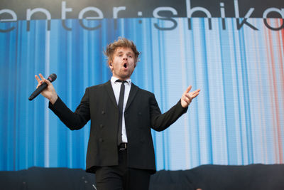Man with arms raised standing against wall