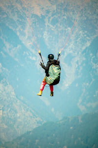Low angle view of man paragliding against mountain