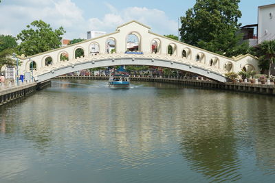 Arch bridge over river in city against sky