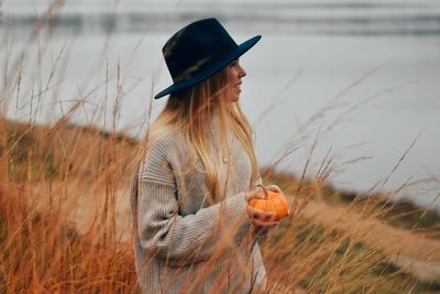 Woman wearing hat standing at lake 