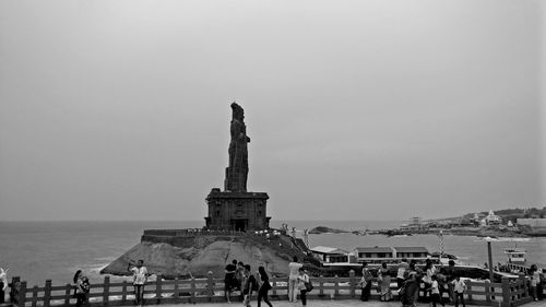 Statue in city against sea