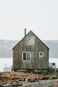 House on field by sea against clear sky