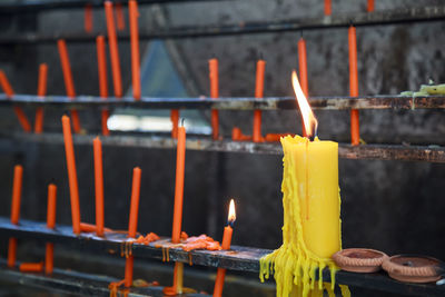 Close-up of lit candles on temple against building