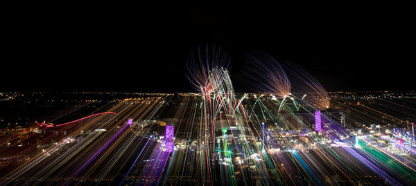 Illuminated ferris wheel in city against sky at night