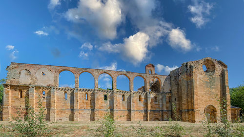 Low angle view of old ruin building against cloudy sky