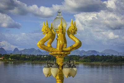 Sculpture by lake against sky