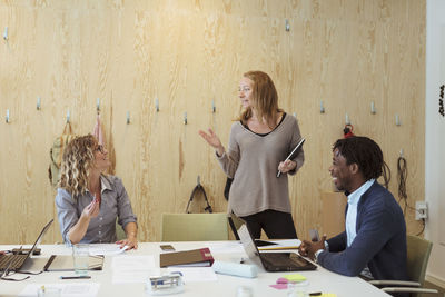 Businesswoman talking with colleagues while standing in board room