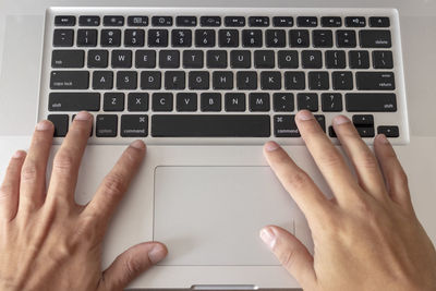 Cropped hands of man using laptop